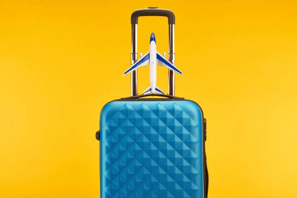 Blue colorful travel bag with handle and toy plane isolated on yellow — Stock Photo