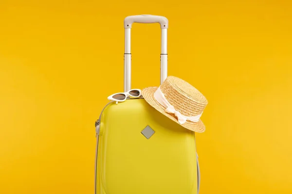 Bolsa de viaje de color amarillo con gafas de sol y sombrero de paja aislado en amarillo - foto de stock