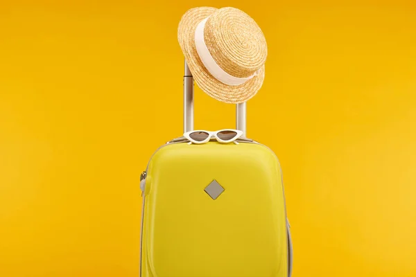 Yellow colorful travel bag with sunglasses and straw hat on handle isolated on yellow — Stock Photo