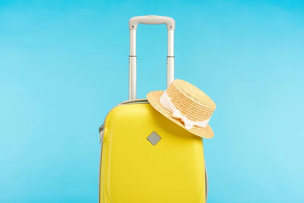Желтый красочный дорожный мешок с соломенной шляпой изолированы на синий — стоковое фото