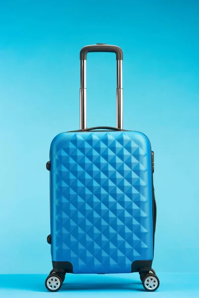 Blue travel bag with handle on wheels on blue background — Stock Photo