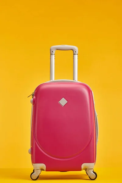 Bolsa de viaje roja con asa sobre ruedas aisladas en naranja - foto de stock