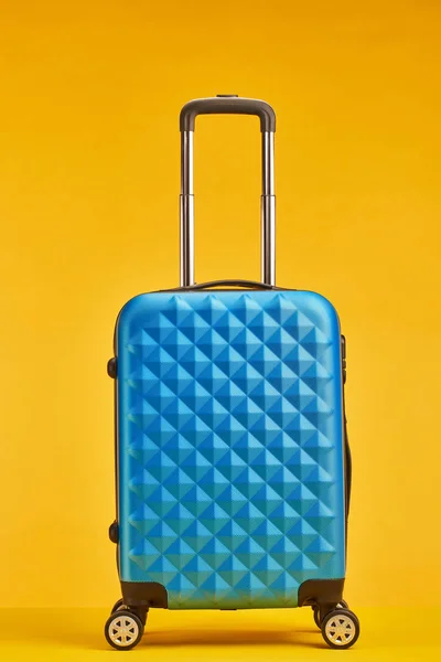 Blue travel bag with handle on wheels isolated on orange — Stock Photo