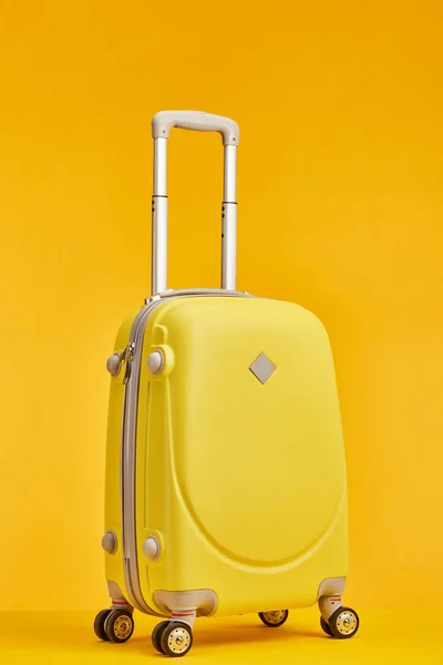 Bolsa de viaje amarilla con asa sobre ruedas aisladas en naranja - foto de stock