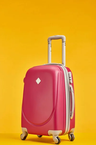 Красный чемодан с ручкой на колесах изолирован на оранжевый — стоковое фото
