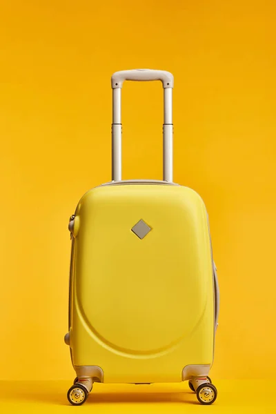 Bolsa de viaje amarilla con asa y ruedas aisladas en naranja - foto de stock