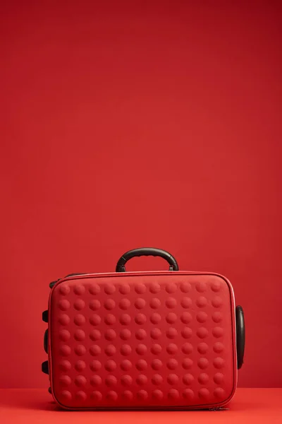 Rote bunt strukturierte Reisetasche isoliert auf rot mit Kopierraum — Stockfoto