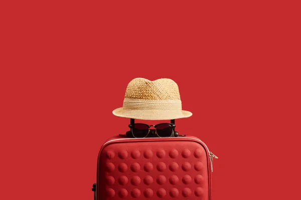 Bolsa de viaje roja con sombrero de paja y gafas de sol aisladas en rojo - foto de stock