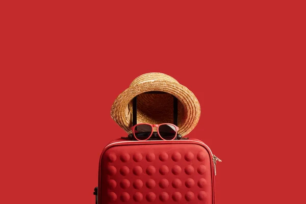 Червоний барвистий туристичний мішок з солом'яним капелюхом і сонцезахисними окулярами ізольовані на червоному — стокове фото
