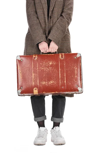 Vista recortada de la mujer en el abrigo de cuadros que sostiene la maleta envejecida vintage aislado en blanco - foto de stock