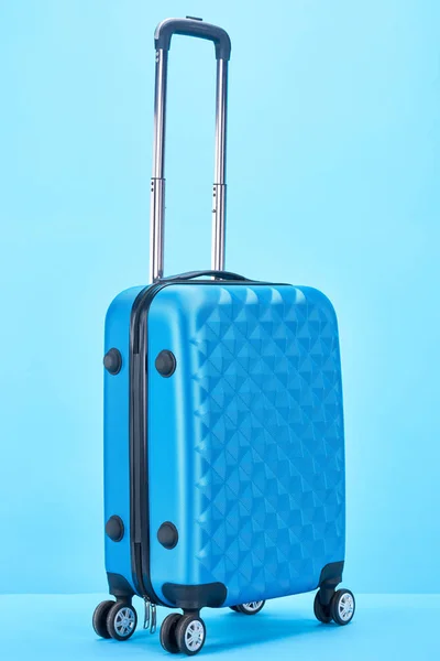 Blaue Reisetasche mit Griff auf Rädern auf blauem Hintergrund — Stockfoto