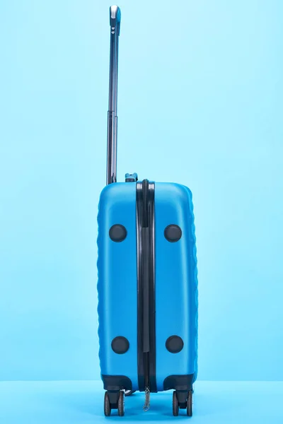 Saco de viagem colorido azul com alça sobre rodas no fundo azul com espaço de cópia — Fotografia de Stock
