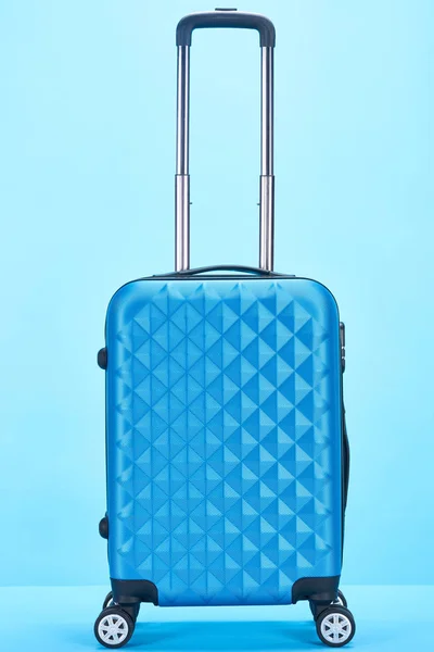 Blue colorful travel bag with handle on wheels on blue background — Stock Photo