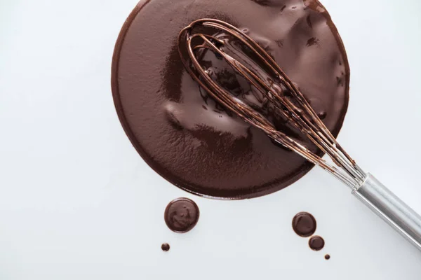 Vista dall'alto della frusta palloncino sporco con cerchio di cioccolato liquido su sfondo bianco — Foto stock