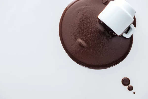 Top view of cup with spilling chocolate and chocolate drops on white background — Stock Photo