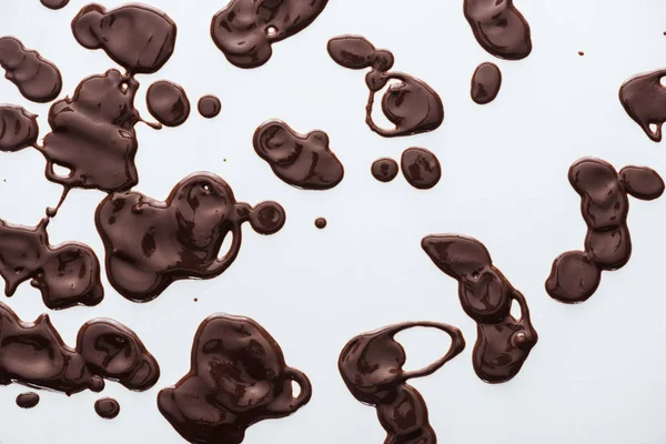Вид зверху краплі розтопленого темного шоколаду на білому тлі — стокове фото