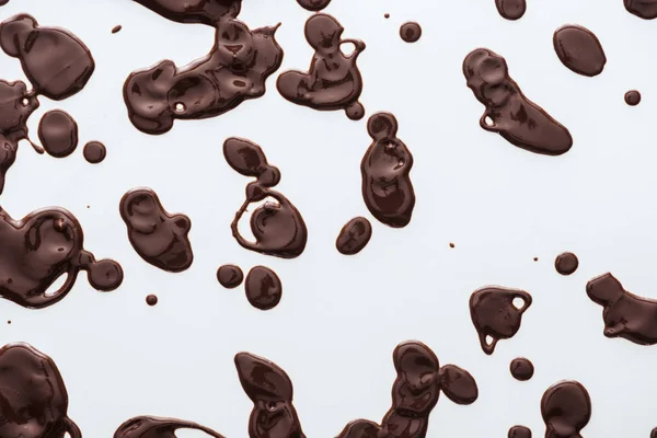 Vue du dessus des gouttes de chocolat noir liquide sur fond blanc — Photo de stock