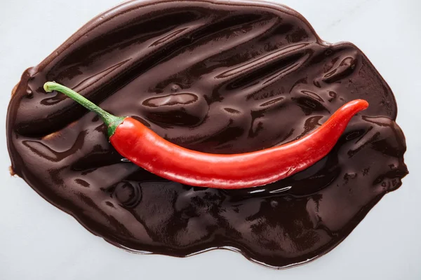 Top view of chili with melted dark chocolate on white background — Stock Photo