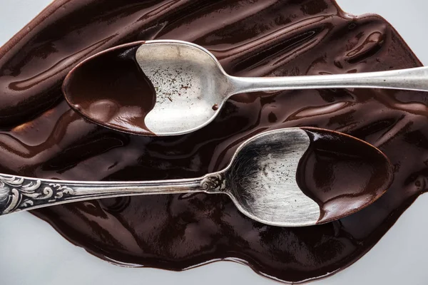 Top view of spoons covered of chocolate and melted chocolate on white background — Stock Photo