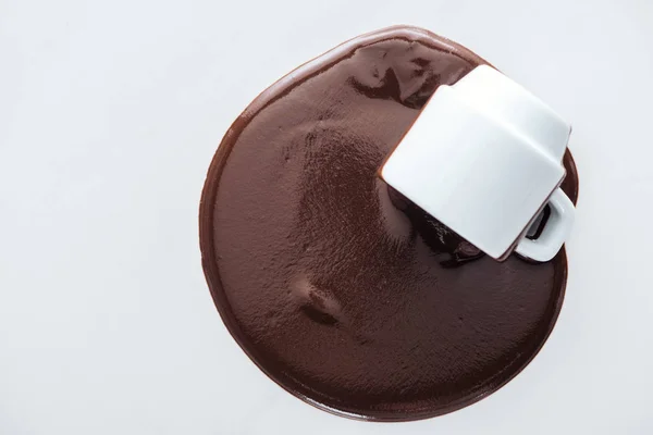 Вид сверху чашки с разливающимся шоколадом на белом фоне — стоковое фото