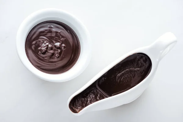 Vue du dessus du bol et du bateau à sauce plein de chocolat noir fondu — Photo de stock