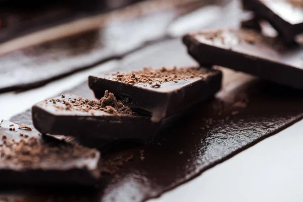 Selective focus of pieces of chocolate bar with cocoa powder and melted chocolate — Stock Photo