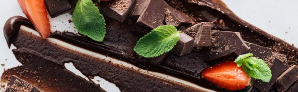 Panoramic shot of pieces of chocolate with fresh mint and strawberries — Stock Photo