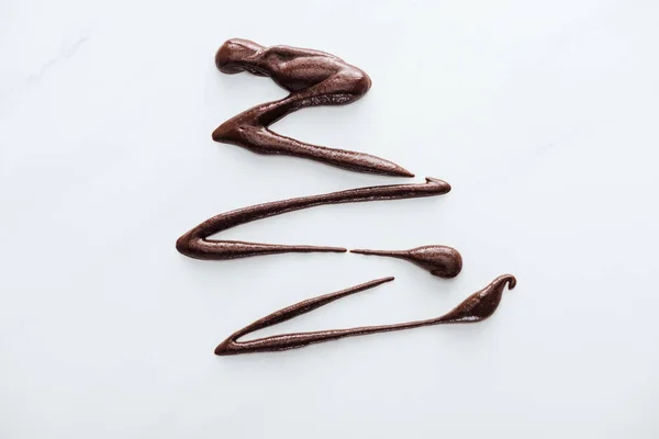 Draufsicht auf verschüttete dunkle flüssige Schokolade auf weißem Hintergrund — Stockfoto