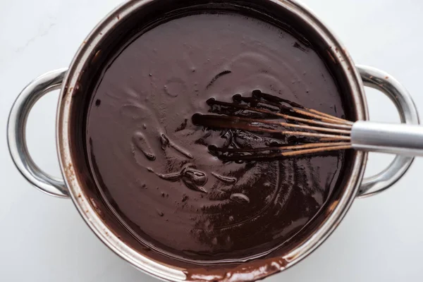 Vue du dessus de la casserole avec chocolat noir fondu et fouet ballon — Photo de stock