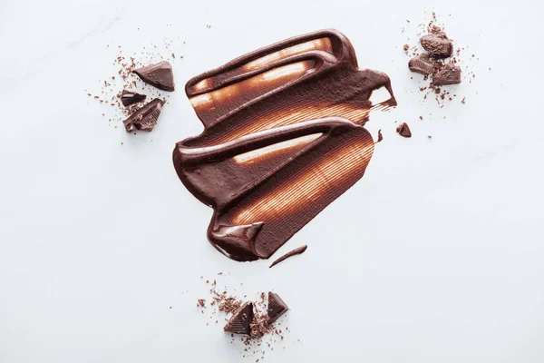 Draufsicht auf flüssige Schokolade mit Schokoladenstücken und Kakaopulver — Stockfoto