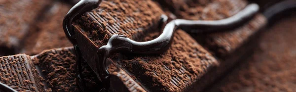 Panoramic shot of pieces of dark chocolate bar with liquid chocolate — Stock Photo