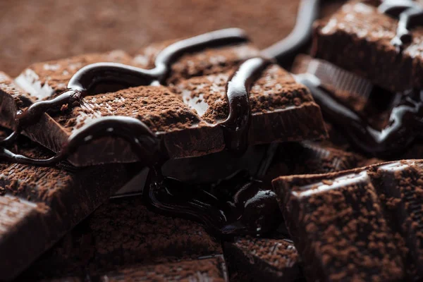 Vista de perto de chocolate derretido com pedaços de barra de chocolate escuro e cacau em pó — Fotografia de Stock