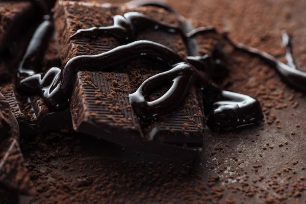 Close up view of chocolate bar with melted chocolate and cocoa powder — Stock Photo
