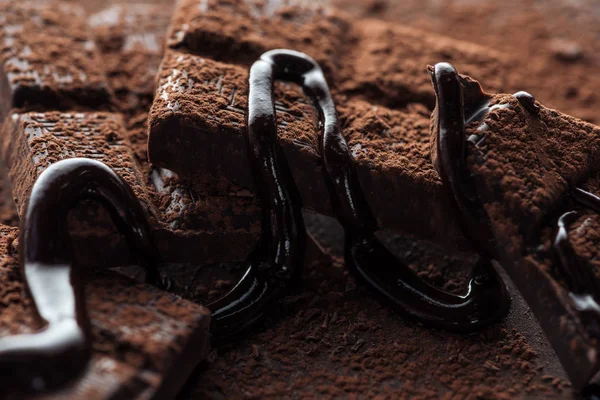 Close up view of chocolate with spilled liquid chocolate ad cocoa powder — Stock Photo