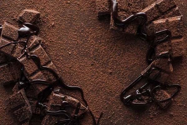 Vista superior de pedaços de chocolate com chocolate líquido e cacau em pó no fundo de metal — Fotografia de Stock