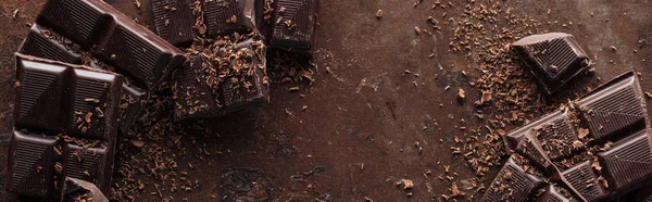 Panoramic shot of pieces of chocolate with chocolate chips on metal background — Stock Photo