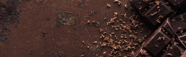 Panoramic shot of pieces of chocolate bar with chocolate chips on metal background — Stock Photo