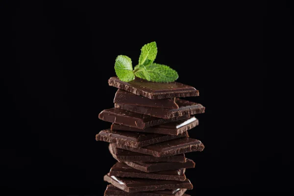Pilha de chocolate escuro com hortelã fresca, isolado em preto — Fotografia de Stock