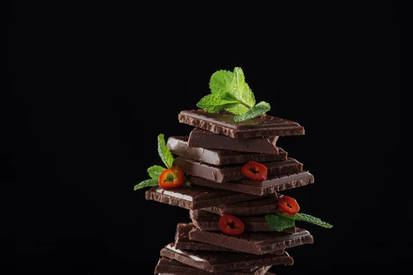 Pile de chocolat noir à la menthe fraîche et au chili, isolée sur fond noir — Photo de stock