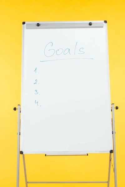 Біла фліпчарт зі списком цілей і копіюванням простору ізольовано на жовтому — стокове фото