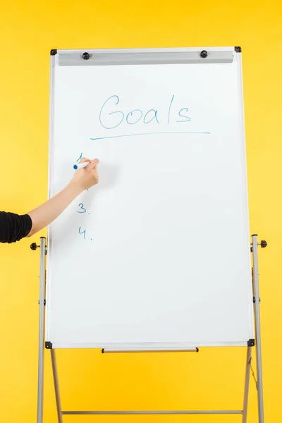 Cropped view of businesswoman writing goals list on white flipchart with copy space — Stock Photo