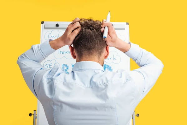 Back view of businessman standing near white office board with words, holding hands on head — Stock Photo