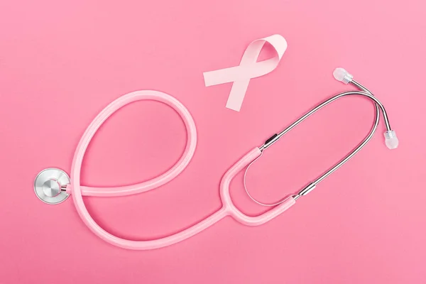 Vista dall'alto dello stetoscopio e del segno del cancro al seno rosa su sfondo rosa — Foto stock