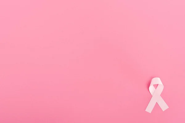 Top view of pink ribbon on pink background with copy space, breast cancer concept — Stock Photo