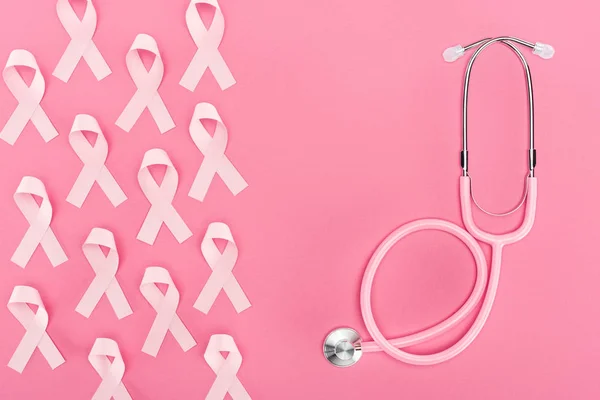 Vista superior do estetoscópio e sinais de câncer de mama rosa no fundo rosa — Fotografia de Stock