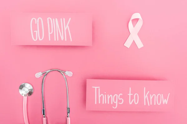 Top view of stethoscope and pink breast cancer sign near go pink and things to know lettering on pink background — Stock Photo