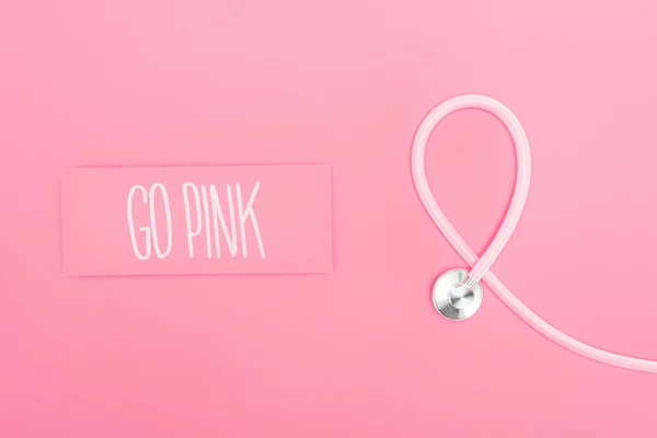 Vista dall'alto dello stetoscopio e andare lettering rosa su sfondo rosa — Foto stock