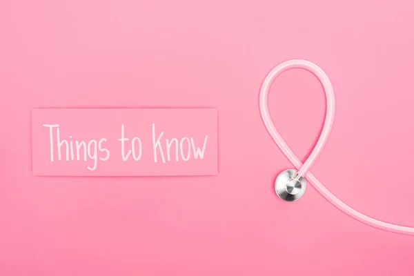 Draufsicht auf Stethoskop und rosa Karte mit Wissenswertem Slogan auf rosa Hintergrund — Stockfoto