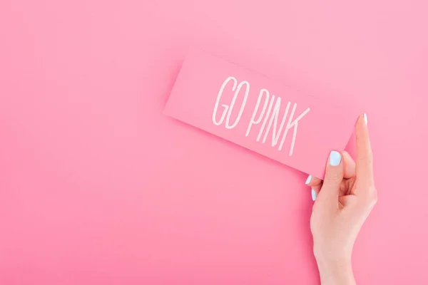 Partial view of woman holding card with go pink lettering on pink background — Stock Photo
