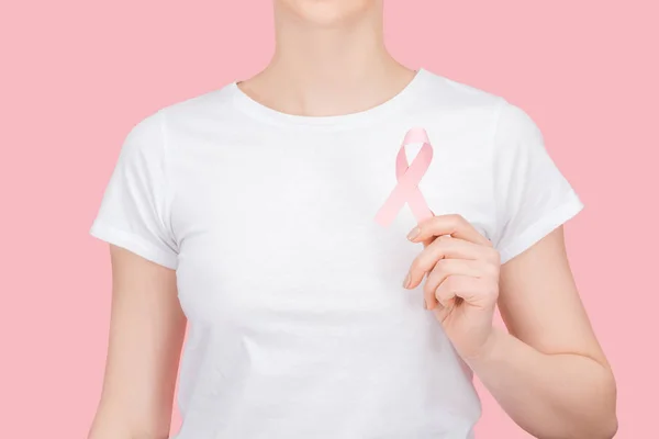 Partial view of woman in white t-shirt holding pink breast cancer sign isolated on pink — Stock Photo